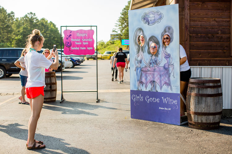 People posing at cut out display in front of Girls Gone Wine store